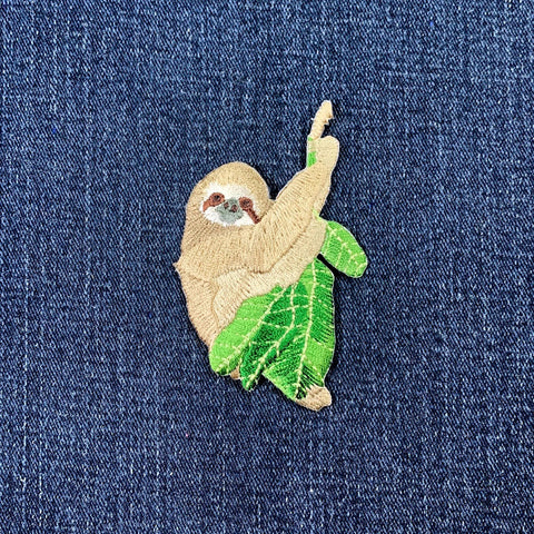 Embroidered sloth patch on a denim background