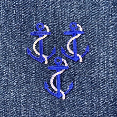 Three blue anchor patches with white rope on a denim background