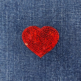 Red heart-shaped sequin patch on blue denim fabric