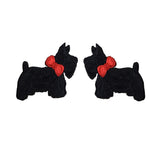 Two black dog-shaped earrings with red bows on a white background