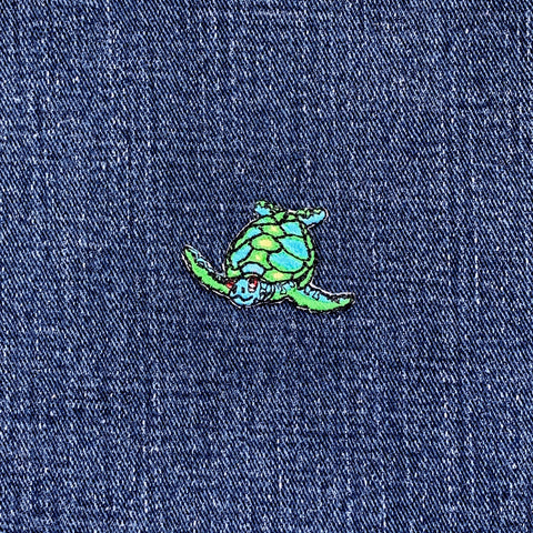 Green and blue sea turtle patch on a denim background