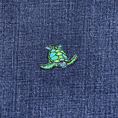 Colorful turtle patch on a denim fabric background
