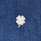 White embroidered four-leaf clover on blue denim fabric