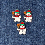 Three snowman patches with red hats and scarves on a denim background