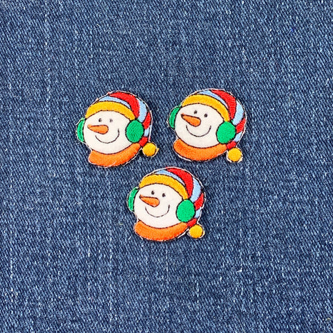 Three colorful snowman patches on a denim background