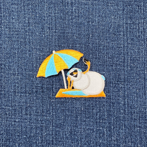 Embroidered patch of a snowman under an umbrella on denim fabric