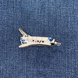 a space shuttle patch on a denim background