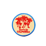 Round patch with red palm trees and 'Surf's Up California' text on a white background