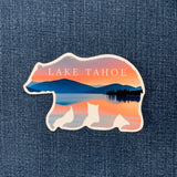 Lake Tahoe bear shaped sticker with mountain and lake design on denim background