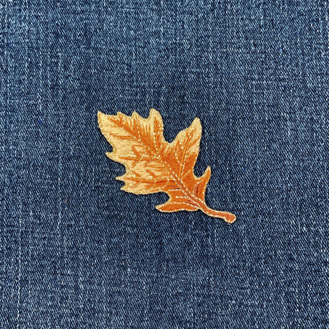 Tan leaf embroidered patch on blue denim fabric