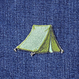 An embroidered green tent patch placed on a textured blue denim background.