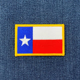 An embroidered patch depicting the Texas flag. The patch has a yellow border and is designed for iron on application.