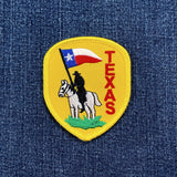 Embroidered patch of a cowboy on a horse with a Texas flag on a denim background