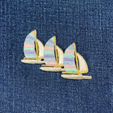 Three sailboat patches with pastel-colored sails on a denim background