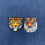 Two tiger head patches on a blue denim background