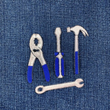 Set of tool patches including pliers, screwdriver, hammer, and wrench on a denim background