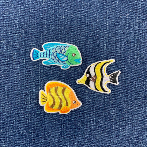 Three colorful fish patches on a denim background