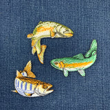 Three embroidered fish patches on a denim fabric background