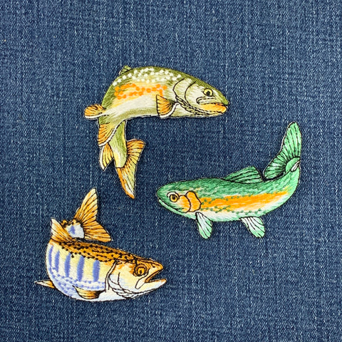 Three embroidered fish patches on a denim fabric background