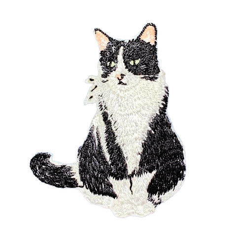 Embroidered patch of a black and white cat on a white background