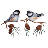 Detailed embroidered patch featuring two black-capped chickadees perched on a brown branch with several pine needles and three pine cones below. 