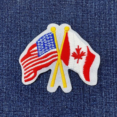 A patch featuring the crossed flags of the United States of America and Canada on a denim background
