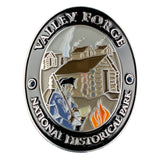 An oval medallion for Valley Forge National Historical Park, featuring a detailed historical illustration of a soldier with a rifle in front of a log cabin and campfire, with the park name engraved around the border.