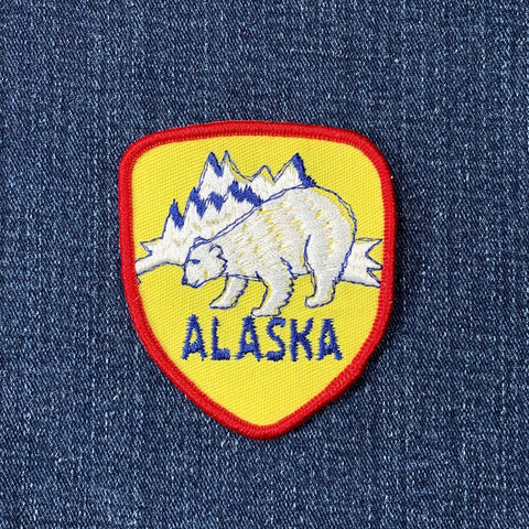 Alaska-themed patch with bear and mountains on a denim background