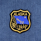 Alaska patch with blue flag and gold text on a blue denim background