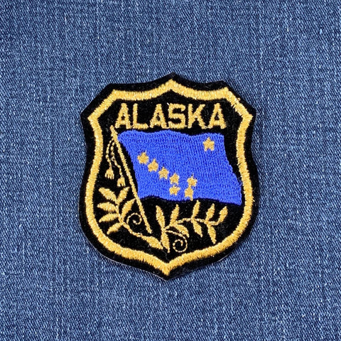 Alaska patch with blue flag and gold text on a blue denim background