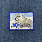 Embroidered patch of a wolf with 'Alaska' text on denim fabric