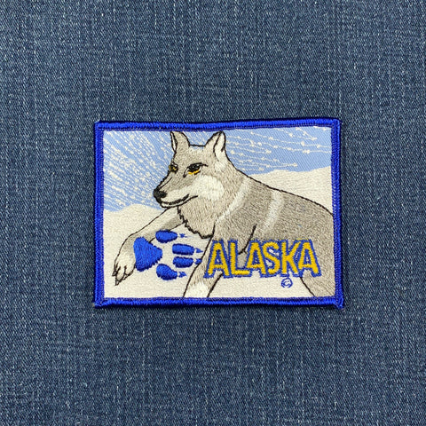 Embroidered patch of a wolf with 'Alaska' text on denim fabric