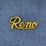 Embroidered patch with 'Reno' text on denim fabric