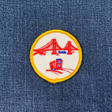 Embroidered patch with a red san francisco golden gate bridge and cable car on a blue denim background