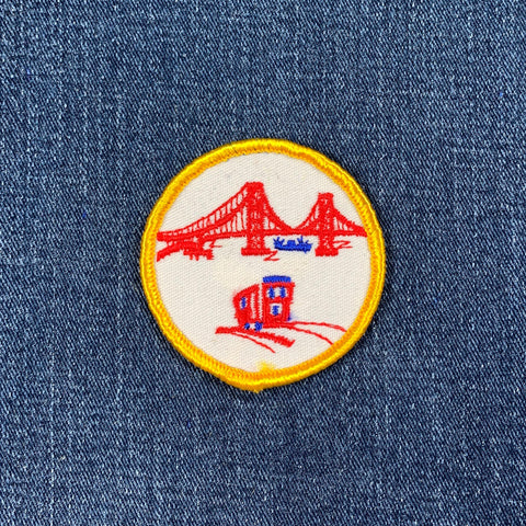 Embroidered patch with a red san francisco golden gate bridge and cable car on a blue denim background