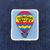 Embroidered patch of a hot air balloon with 'Sonoma Valley' text on a blue denim background.