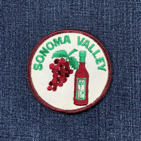 A circular embroidered patch featuring a cluster of dark red grapes and a bottle of red wine against a white background. The words 'SONOMA VALLEY' are stitched in green text around the top curve, displayed on a denim background.