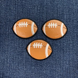Three football-shaped patches on a denim background