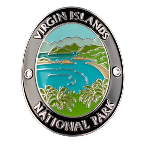 An oval medallion featuring a colorful landscape of Virgin Islands National Park with turquoise water, green hills, and palm trees, surrounded by a black and silver border with raised white text.