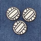 Three volleyball-shaped patches on a denim background