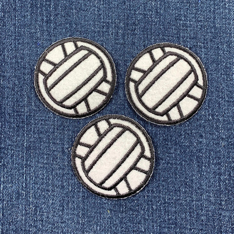 Three volleyball-shaped patches on a denim background