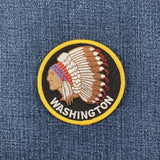 Embroidered patch of a Native American headress with 'Washington' text on denim fabric.