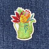 Embroidered patch of a watering can with flowers on denim fabric