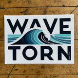 Sticker with 'WAVE TORN' design displayed on a wooden surface