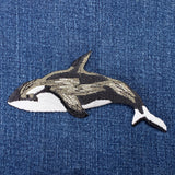 Embroidered orca whale patch on denim fabric