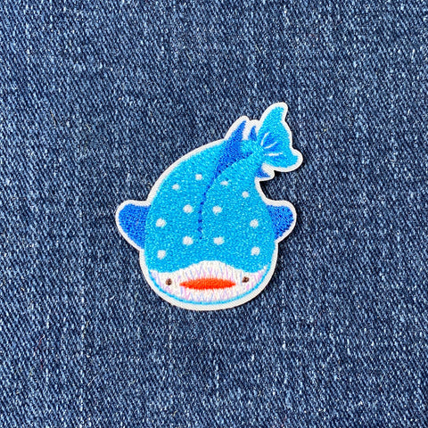 Embroidered patch of a blue whale on denim fabric