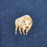 Embroidered white buffalo patch on a denim background
