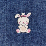Embroidered bunny patch with a pink bow on denim fabric