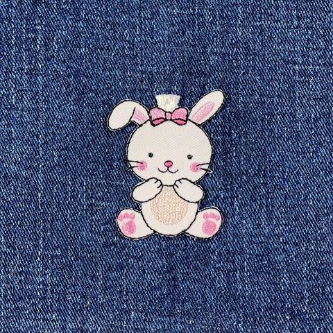 Embroidered bunny patch with a pink bow on denim fabric