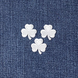 Three white shamrock-shaped patches on a blue denim background